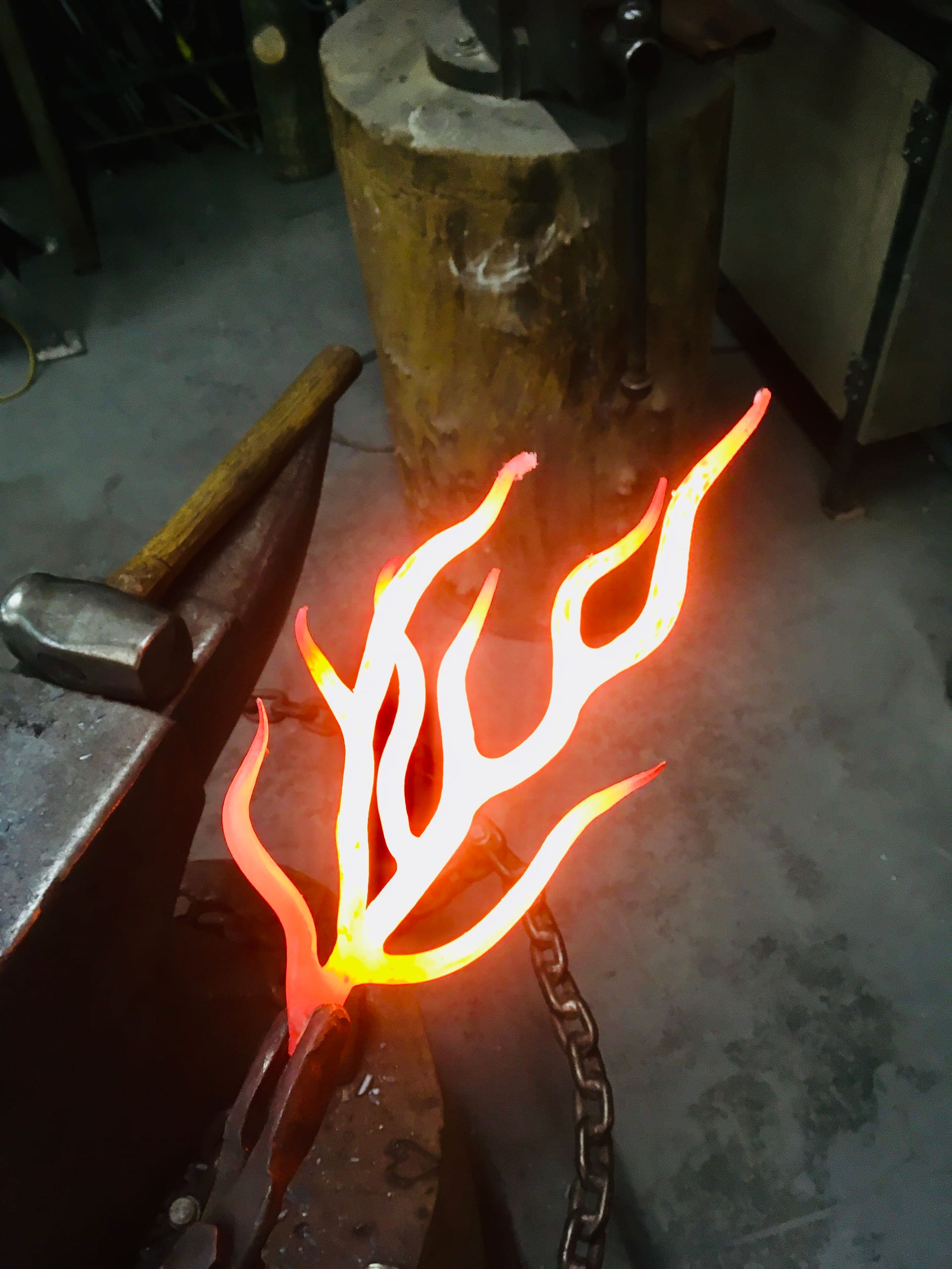 A branched piece of steel glowing white hot, held at the anvil