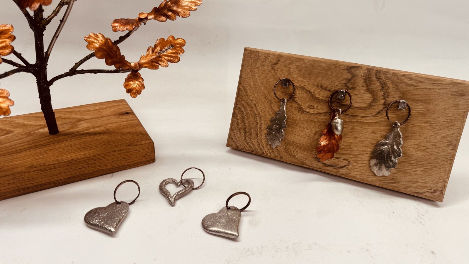 Pewter and copper oak leaf keyrings on an oak board, with pewter hearts and a little copper tree
