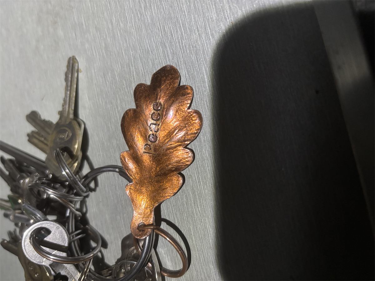 A personalised copper leaf keyring in use
